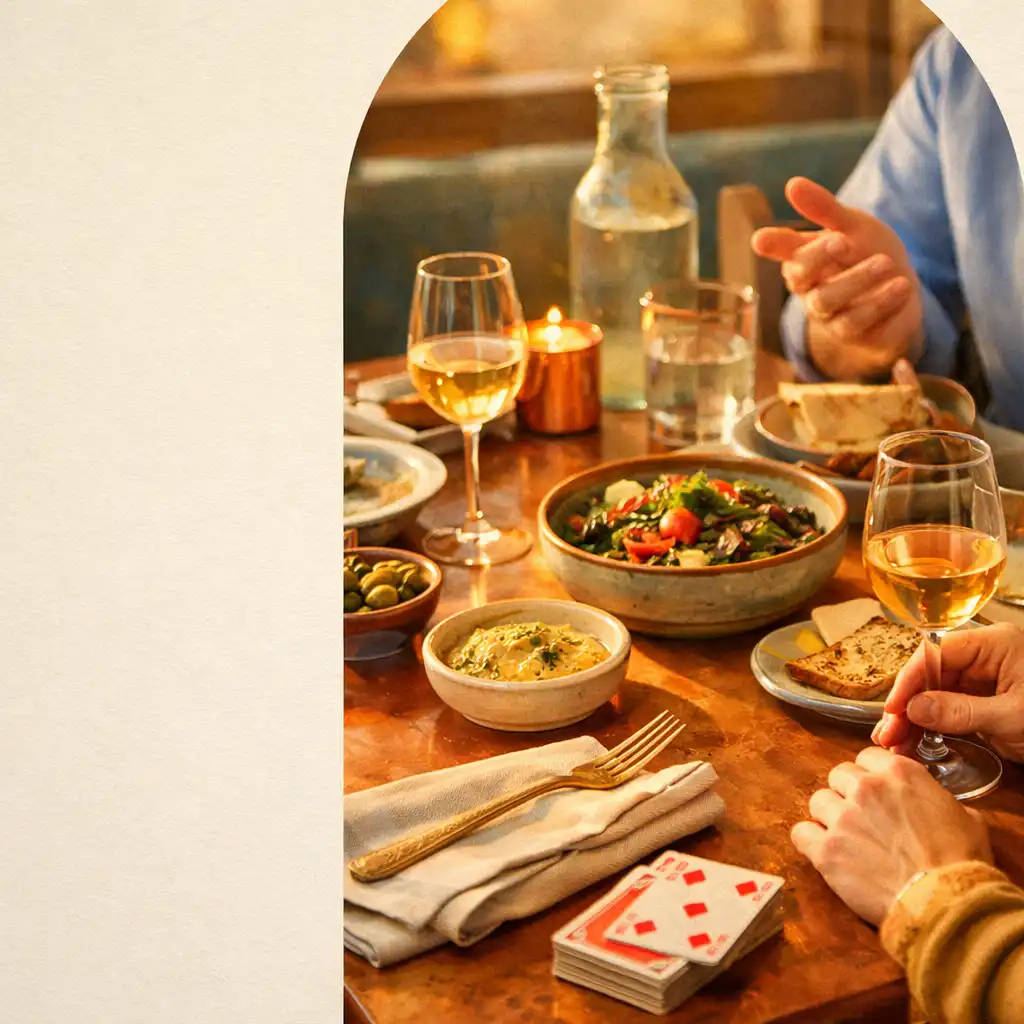 Shared supper table with dishes, linen napkins, cards and hands in conversation